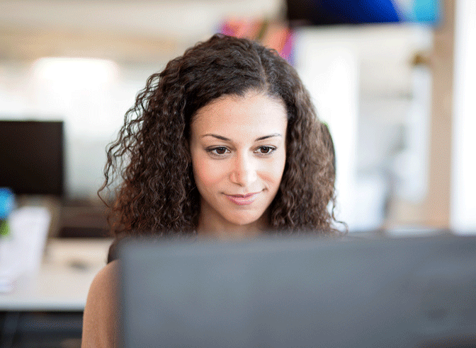 A rotating image. Image 1 A woman is pleased as she looks at a computer screen Image 2 A woman engaged happily with someone across a table from her Image 3 A clinician looks down at a tablet